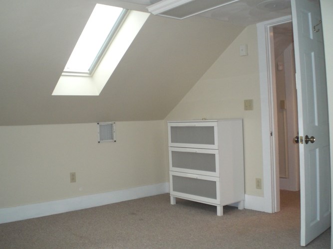 A room with a skylight and a white cabinet.