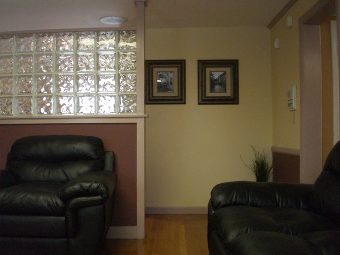 Two black leather chairs in a room with a window.