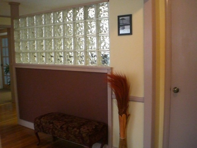 A broom stands in a hallway next to a bench.