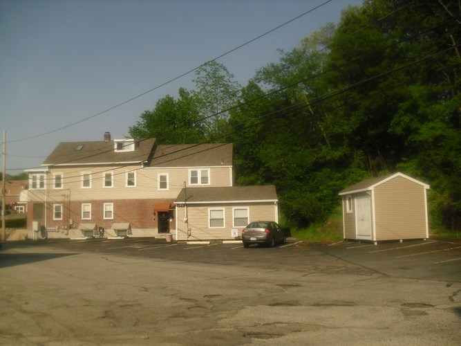 A parking lot with a house and a shed.