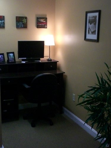 A black computer desk with a monitor, lamp, and chair.