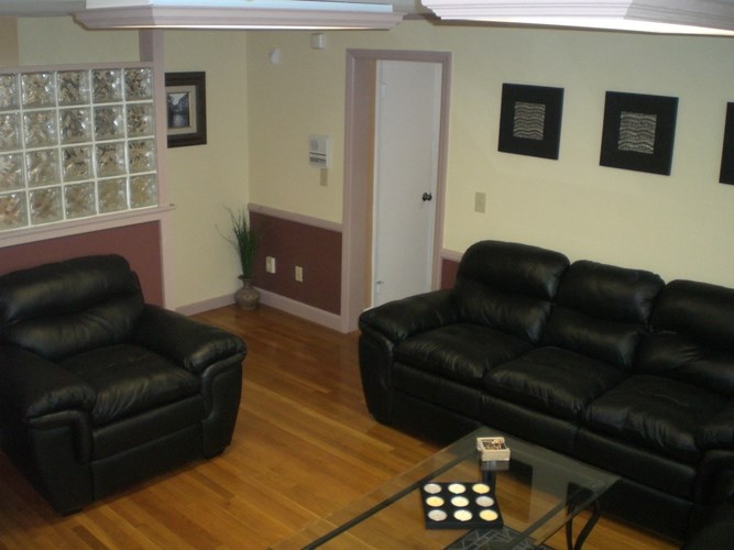 A living room with a black leather couch and chair.
