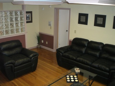 A living room with a black leather couch and chair.