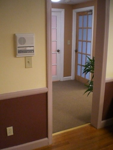 A wall-mounted thermostat is on a wall next to a door.