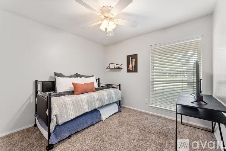 A bedroom with a bed, a table, and a ceiling fan.