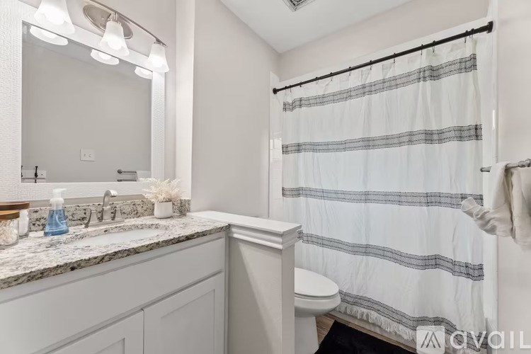 A bathroom with a white shower curtain and a marble countertop.