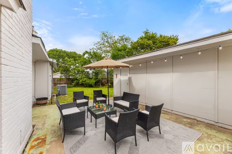 A patio with a glass table surrounded by chairs and an umbrella.