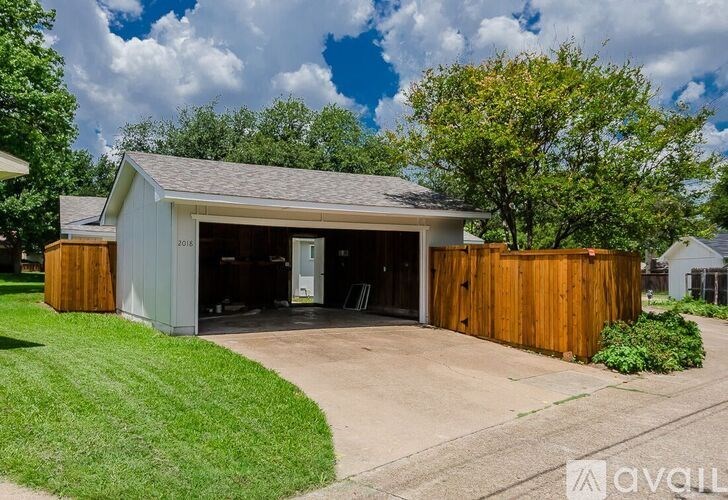 A detached garage with a white exterior and a brown fence.