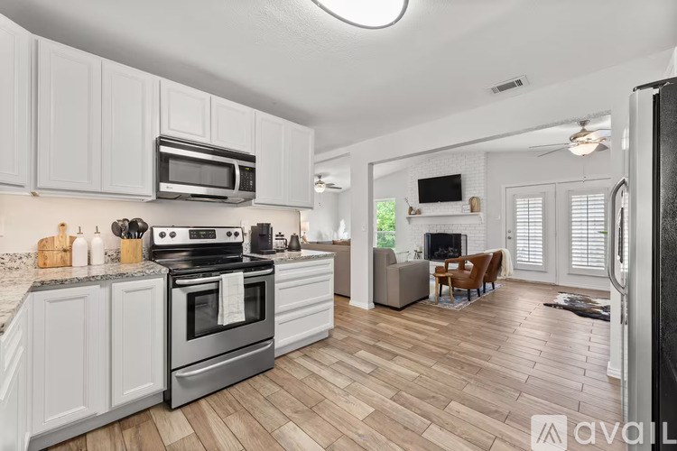 A kitchen with white cabinets and a wooden floor.