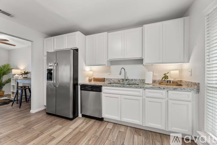 A kitchen with white cabinets and a stainless steel refrigerator.