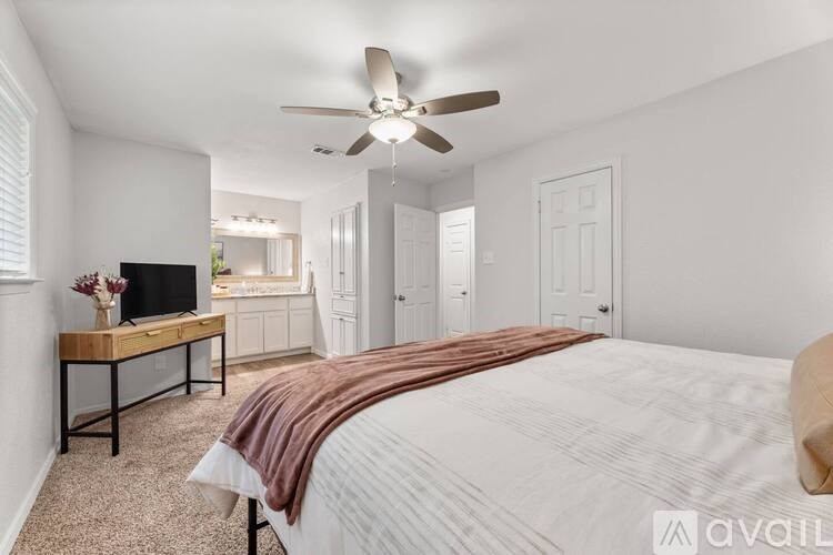 A bedroom with a bed, a television, and a ceiling fan.