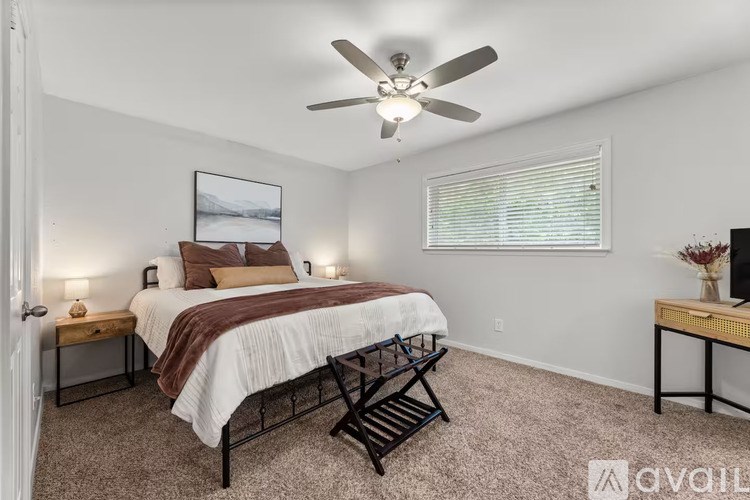 A bedroom with a bed, chair, and a painting on the wall.