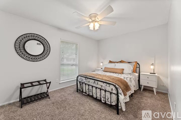 A bedroom with a bed, nightstand, and window with blinds.
