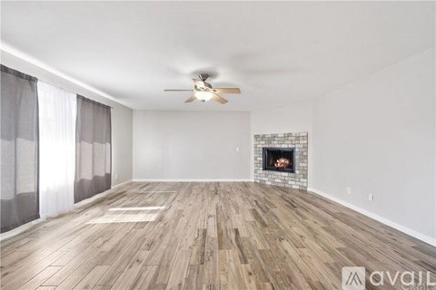 A spacious room with a fireplace and wood flooring.