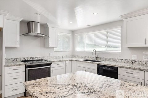 A kitchen with white cabinets and granite countertops.