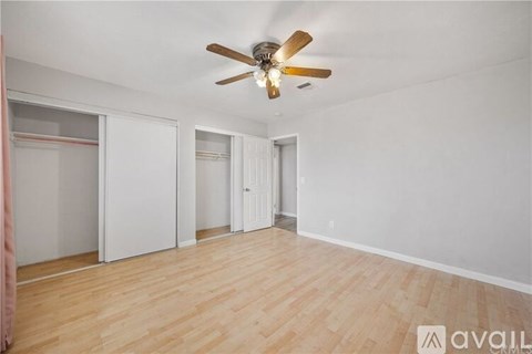 A room with a ceiling fan and wooden flooring.