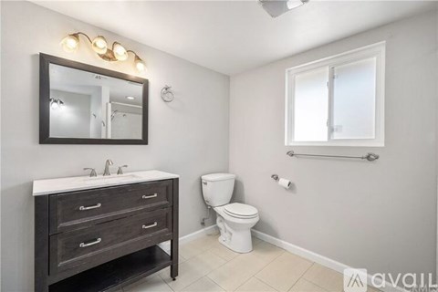 A bathroom with a toilet, sink, and mirror.