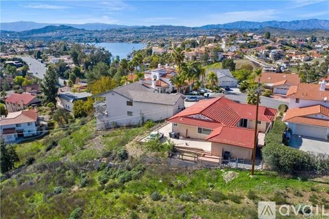 A bird's eye view of a residential area with houses and a body of water in the distance.