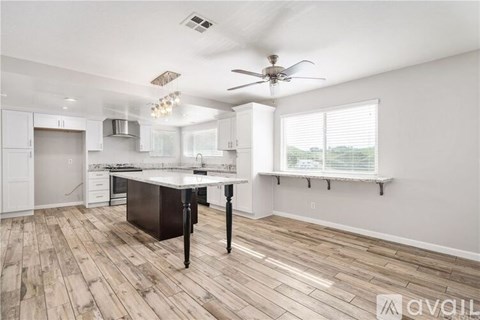 A kitchen with a black island and wooden floors.