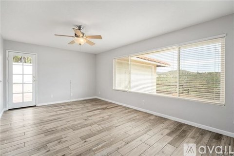 A room with a ceiling fan and wooden flooring.