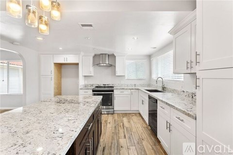 A kitchen with white cabinets and a marble countertop.