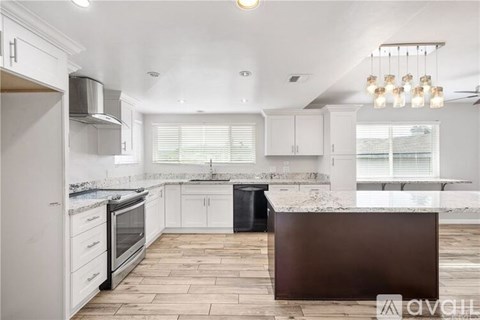 A kitchen with white cabinets and a wooden island.