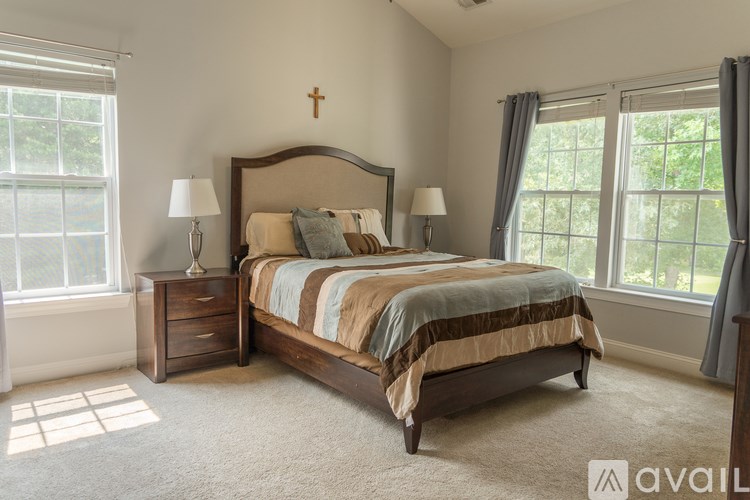 A bedroom with a large bed, two lamps, and a cross on the wall.