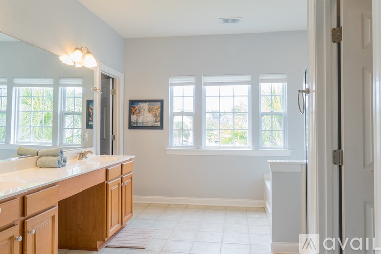 A bathroom with a large mirror, a sink, and a window.