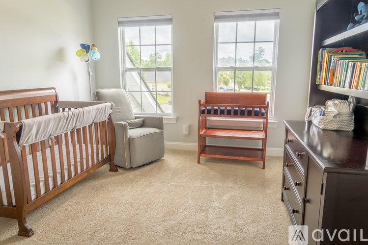 A baby nursery with a crib, chair, and shelves.