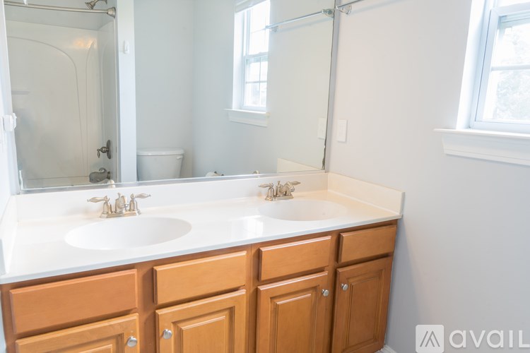 A bathroom with a white countertop and brown cabinets.