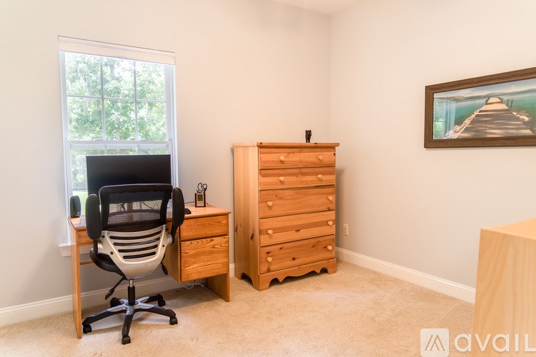 A room with a desk, chair, and a wooden cabinet.