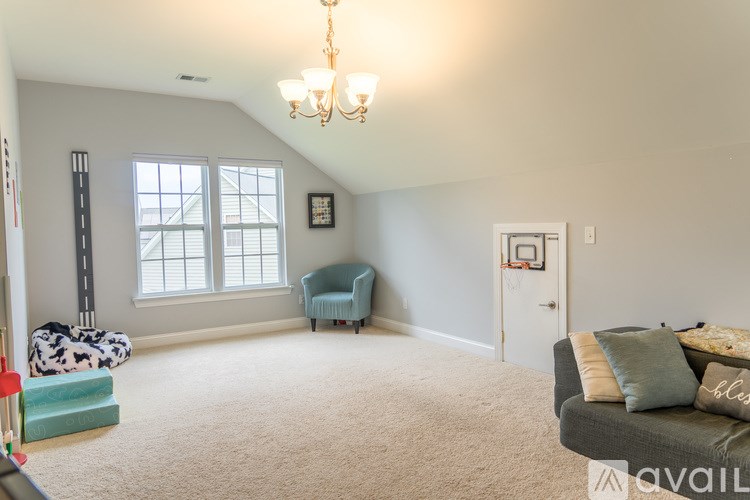 A living room with a grey couch and a chandelier.