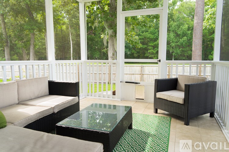 A patio with a white couch, a black chair, and a glass table.
