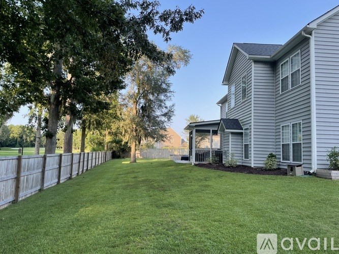 A house with a fence and a tree in front of it.