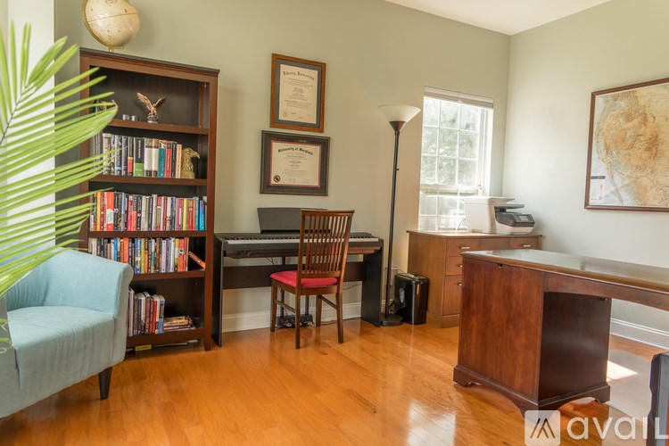 A room with a bookshelf, chair, desk, and a map on the wall.