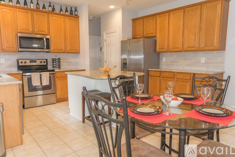A kitchen with a table set for two with a red tablecloth.