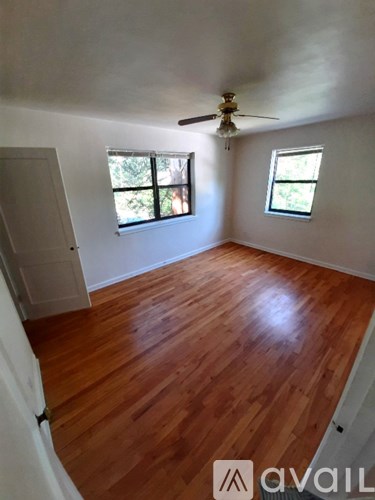 A room with wooden floors and two windows.