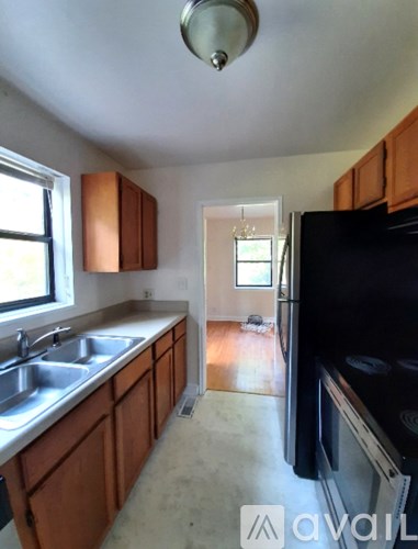 A kitchen with wooden cabinets and a black fridge.