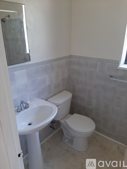A bathroom with a toilet, sink, and tiled walls.