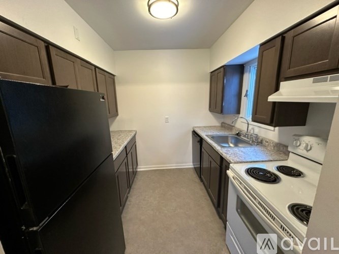 A kitchen with black appliances and brown cabinets.