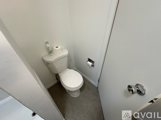 A white toilet with a roll of toilet paper on top of it.