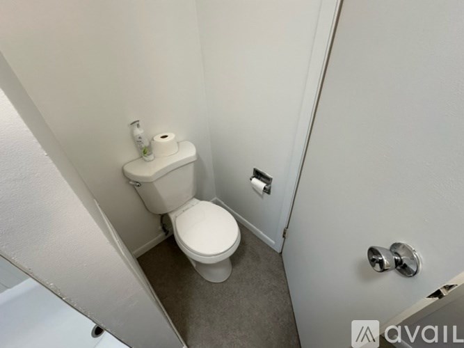 A white toilet with a roll of toilet paper on top of it.