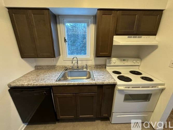 A kitchen with brown cabinets and a white stove top oven.