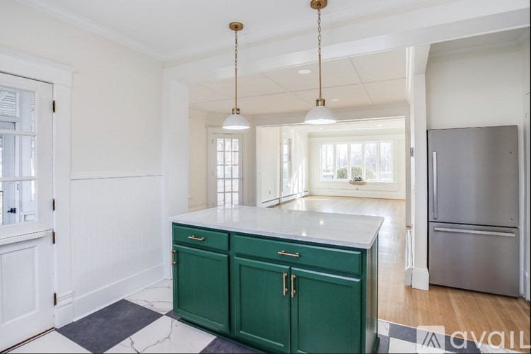 A kitchen with green cabinets and a marble countertop.