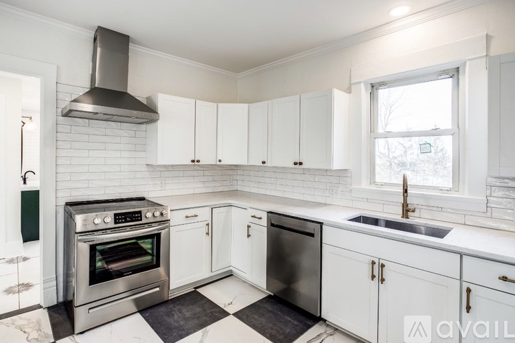 A kitchen with white cabinets and a black and white checkered floor.