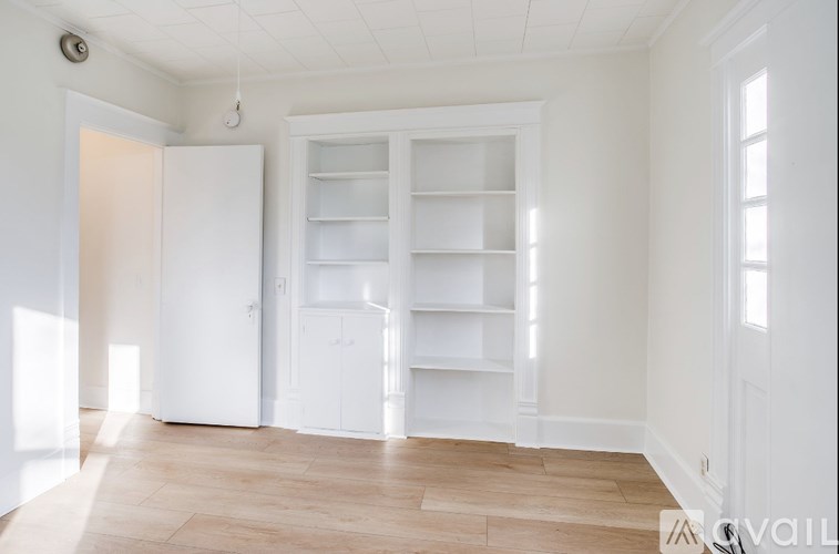 A white room with a large open door and a cabinet with shelves.