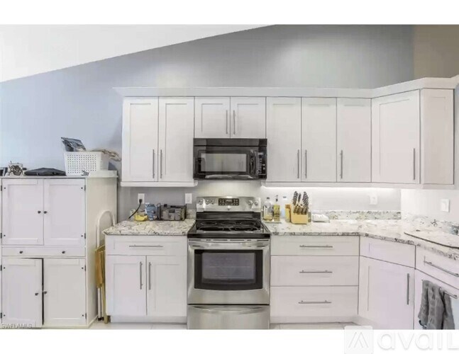A kitchen with white cabinets and appliances.