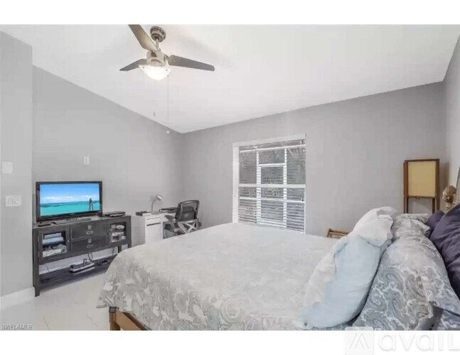 A bedroom with a bed, a television, and a ceiling fan.