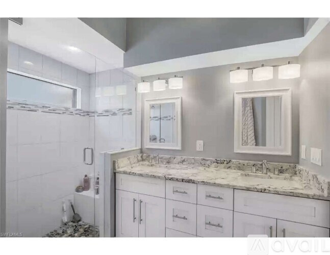 A modern bathroom with a marble countertop and white cabinets.