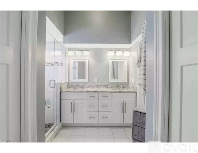 A bathroom with a marble countertop and white cabinets.